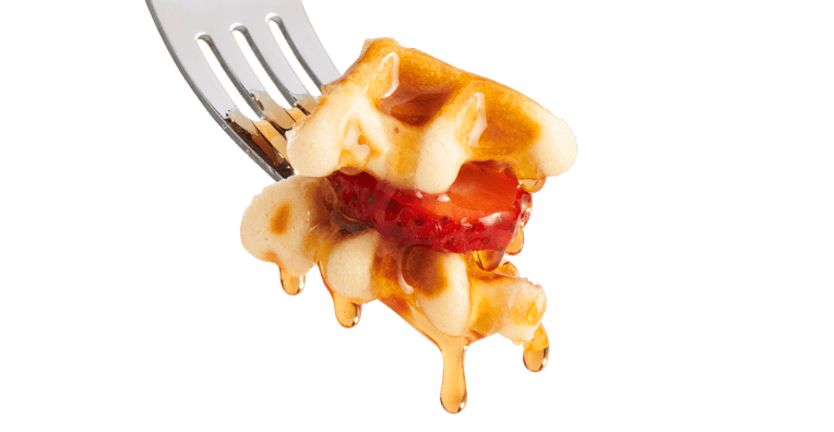 A fork holding a bite of waffle topped with a strawberry slice and dripping syrup, against a white background.