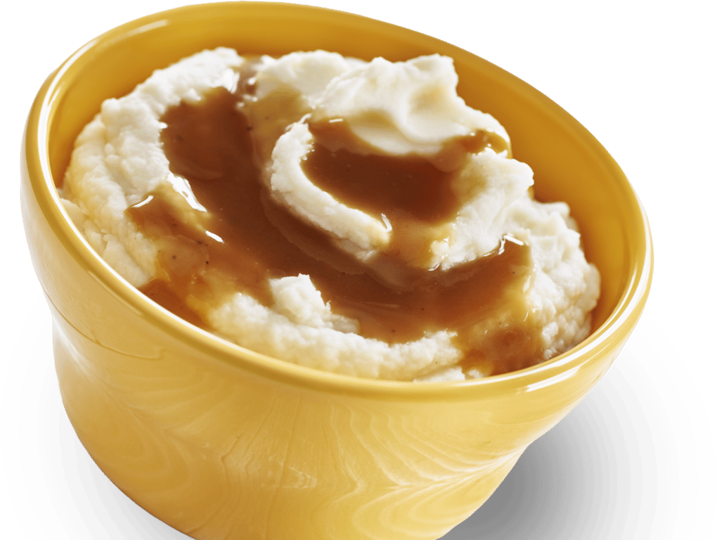 A yellow bowl filled with creamy mashed potatoes topped with brown gravy.