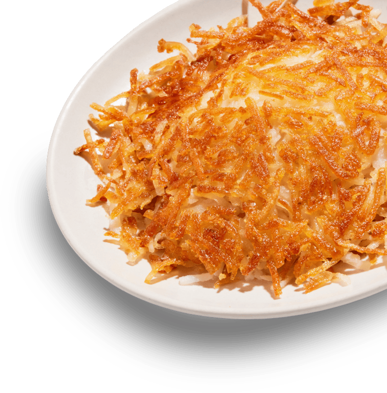 A close-up of crispy, golden-brown hash browns on a white plate.